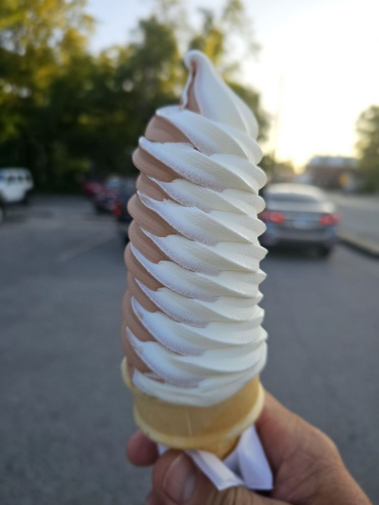 A tall chocolate and vanilla twist cone held outside Dairy Haven